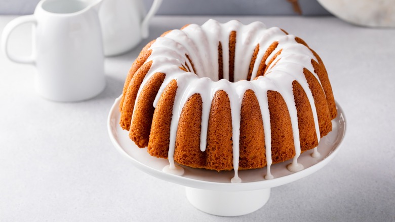 An iced vanilla and orange bundt cake on a stand