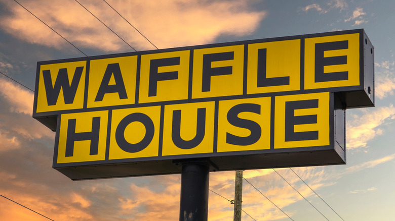 The sign outside of a Waffle House with a colorful sky in the background