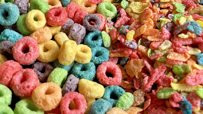 Close up of multicolored Froot Loops and Fruity Pebbles cereals poured into the same bowl