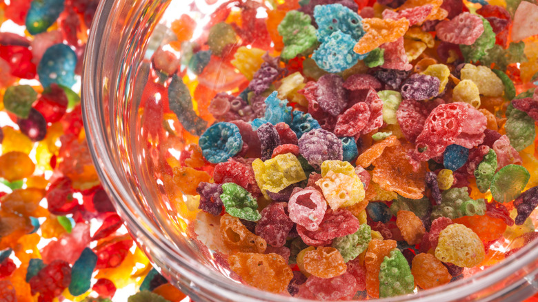 A close up of red, blue, purple, green, yellow and orange pieces of Fruity Pebbles cereal in a clear bowl