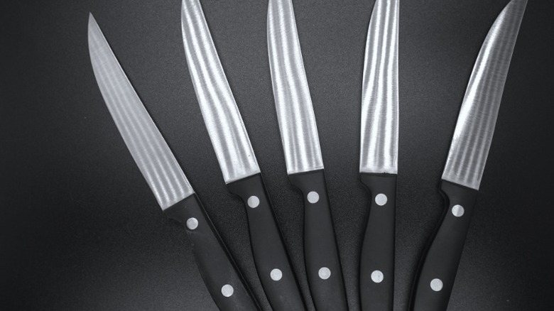 A set of steak knives with black handles that look similar to steak knives from Longhorn Steakhouse.
