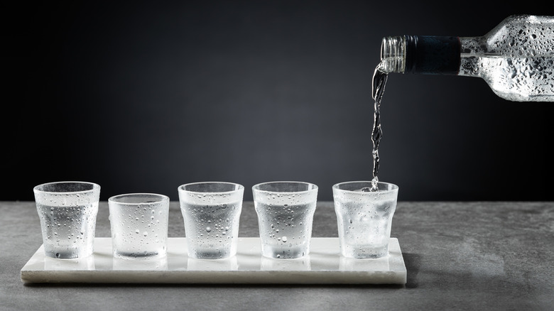 a bottle pouring multiple vodka shots