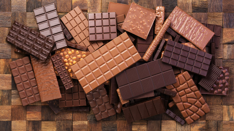 Different kinds of unnamed chocolate bars placed erratically on top of a wooden background