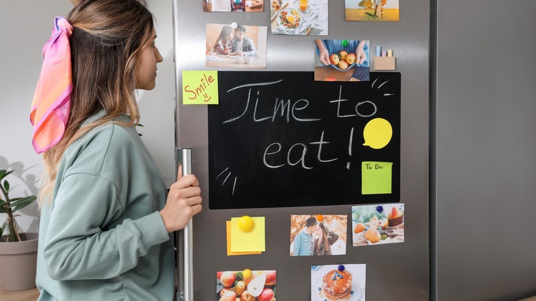 A girl opens a typical home fridge