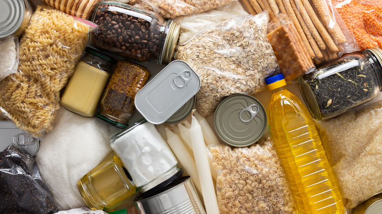 A flat lay of neatly packed pantry essentials, including oatmeal, pasta, coffee beans, cooking oil, canned goods, and more