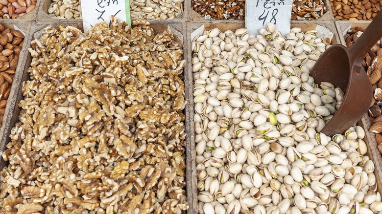 Walnuts and pistachios side by side at an outdoor market.