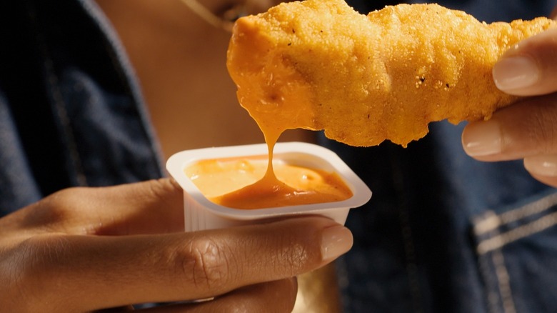 Person holding a sauce-dipped McDonald's McCrispy Strip close-up