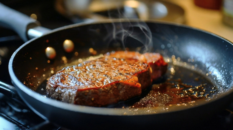 A steak searing in a frying pan.