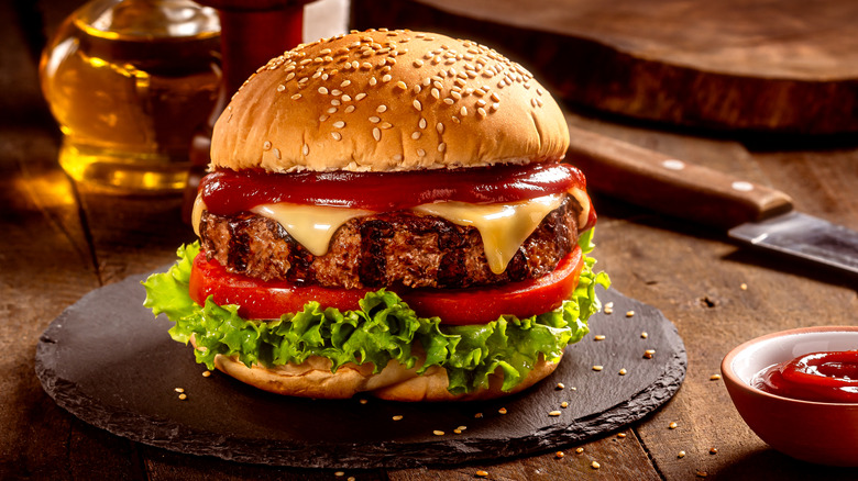Cheeseburger with lettuce and tomato on a sesame seed bun