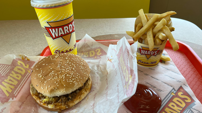 A Ward's burger on a tray with fries, ketchup and a drink.
