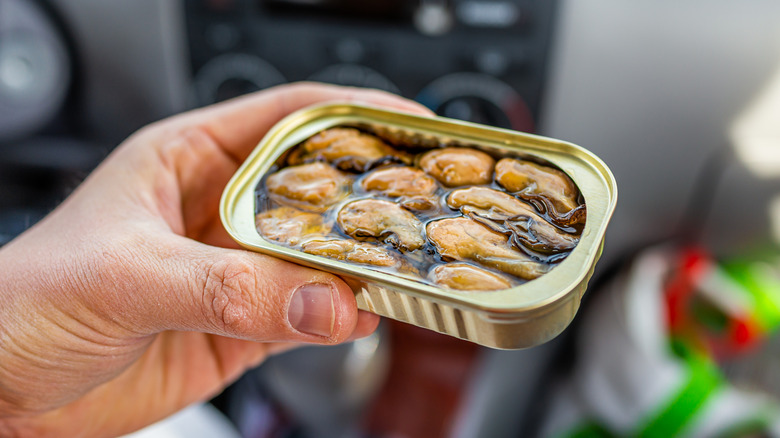 Hand holding canned oysters in oil