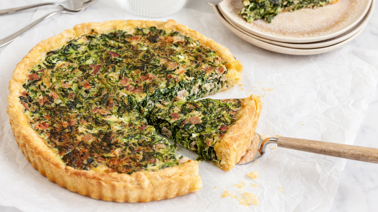 Cottage cheese, spinach, and ham quiche with a serving spatula under a slice.