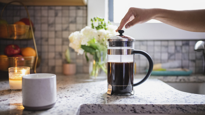 hand pushing down the plunger of a French press