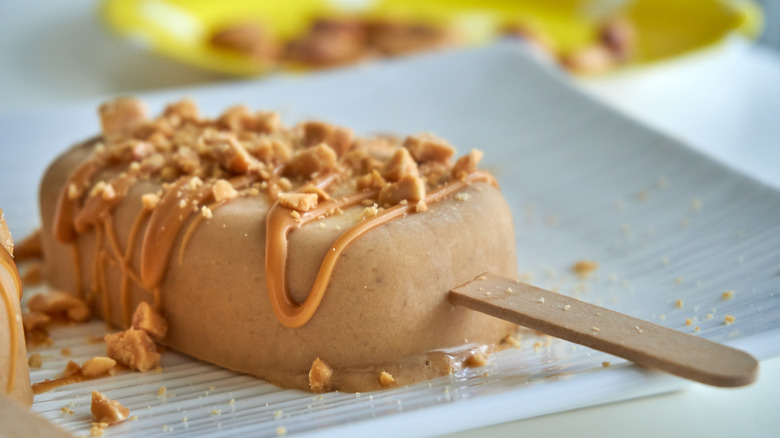 closeup of peanut butter popsicle with caramel drizzle and sweet crumbles