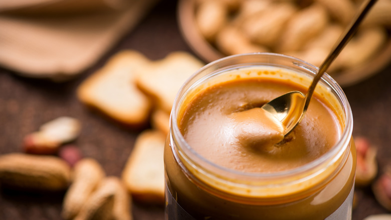spooning out creamy peanut butter from jar to prepare for freezing