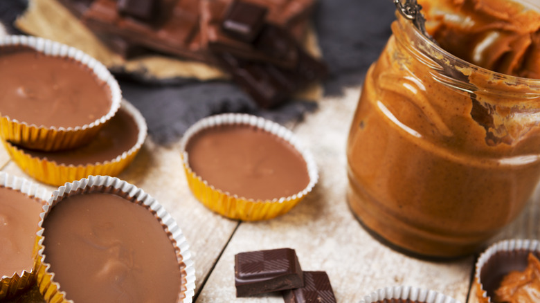 frozen peanut butter cups site beside chocolate squares and a jar of peanut butter