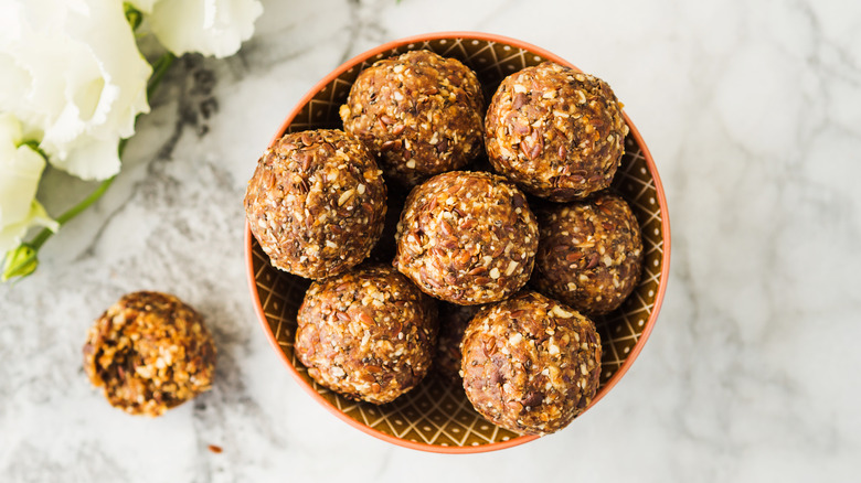 frozen peanut butter oatmeal balls sit in a bowl on a white marble surface