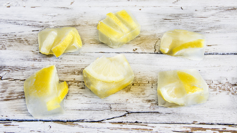 Lemon ice cubes on wooden background.