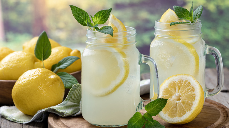 Lemonade in mason jar glasses with fresh mint next to lemons.