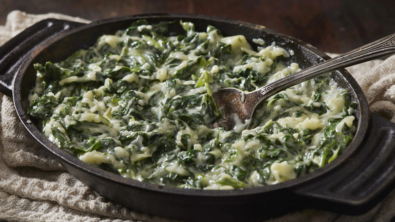Cast iron dish full of creamy spinach sauce.