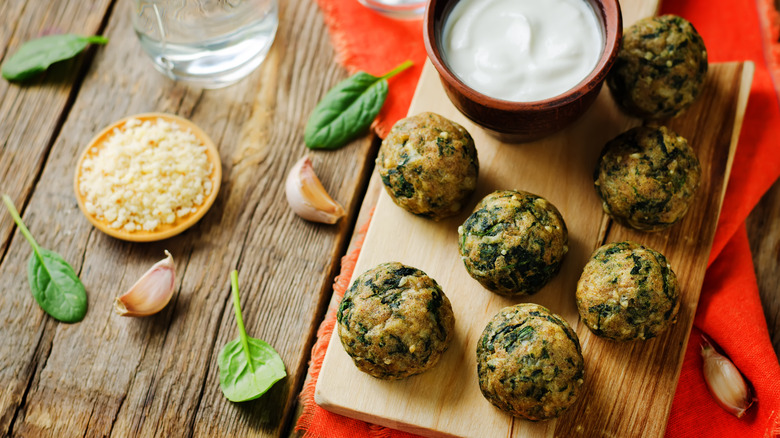 Cutting board full of freshly made spinach balls.