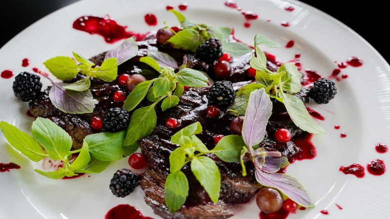 A blackberry and pomegranate dish with basil leaves