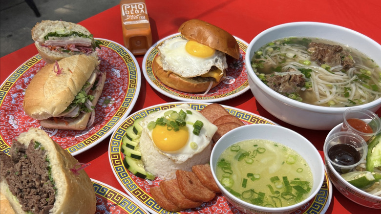 A table covered with bahn mi sandwiches, pho, spam and eggs, and other delicious dishes