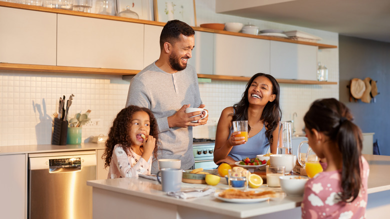 A family of four shares a meal and laughter around their kitchen island.