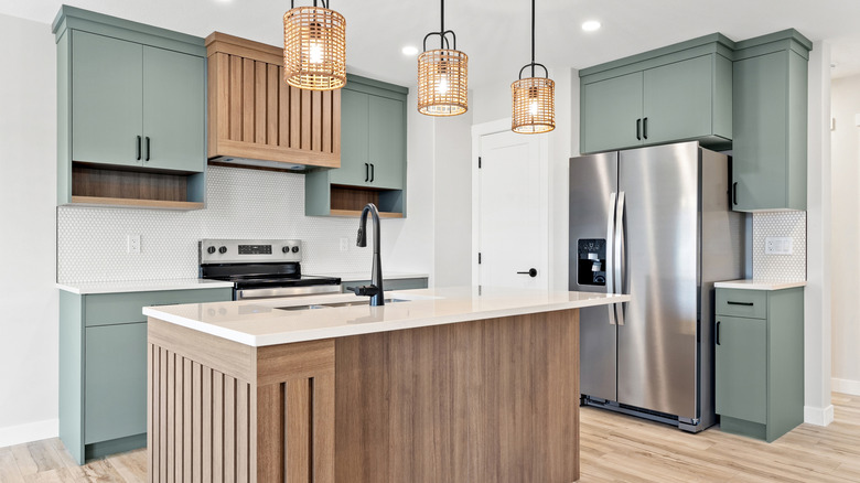 A bright kitchen with wood and sage-green accents, complete with a spacious island.