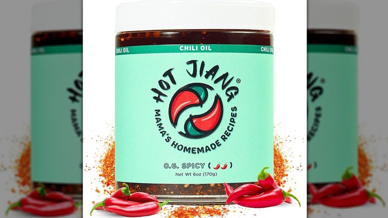 a jar of Hot Jiang chili oil on a white background with spices and peppers