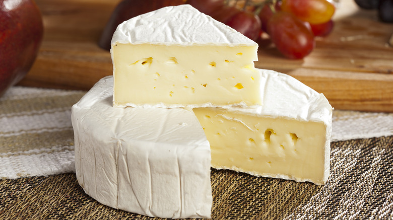 White brie cheese with wedge cut out and placed on top