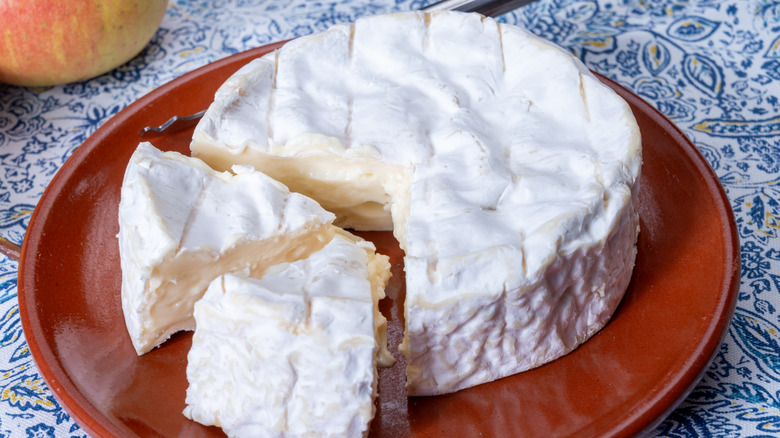 Camembert cheese with two wedges sliced on a plate