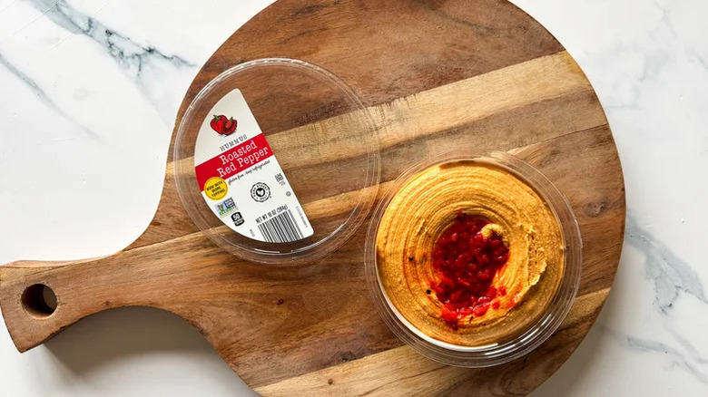 Aldi's roasted red pepper hummus served on a wooden cutting board