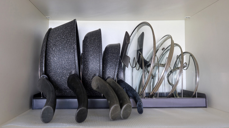 A shelf with a row of various pans with matching lids