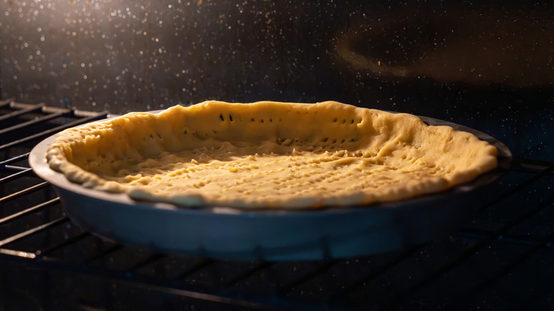 A tin of pie crust baking in an oven.