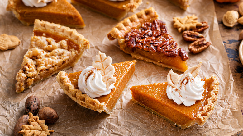 Slices of pumpkin, pecan, and berry pie styled together.