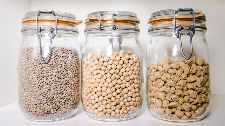 Three Mason jars hold dry goods on a kitchen shelf.
