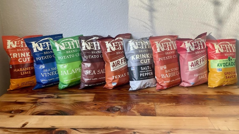 Collection of different flavored Kettle Brand Potato Chip Bags lined up on a wooden table