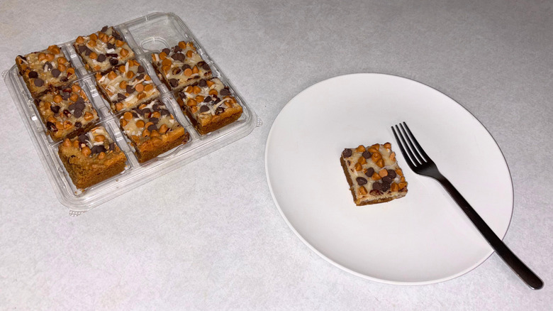 Tray of dessert bars with one on a white plate with fork.