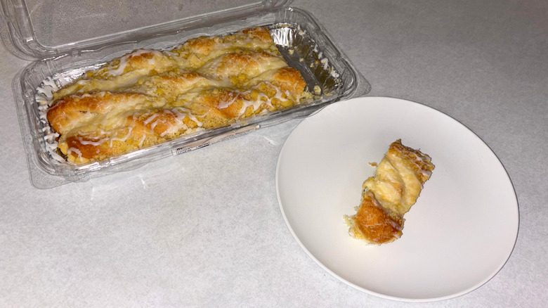 Cheese danish in a tray and one slice on a white plate.