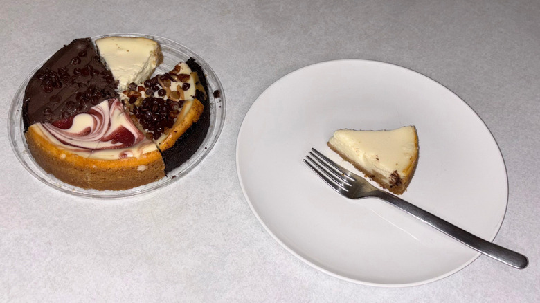 Four flavors of cheesecake on a tray and a piece of plain cheesecake on a plate with a fork.