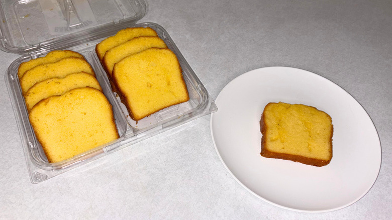 Slices of lemon cake in a tray and one piece on a white plate.