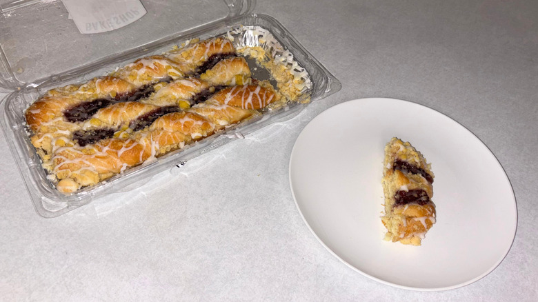 Raspberry danish in a tray and one piece on a white plate.
