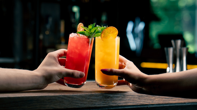 Two people cheering with their cocktails