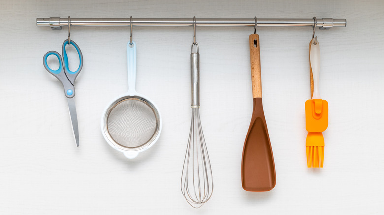 a kitchen rail with five tools hanging from it