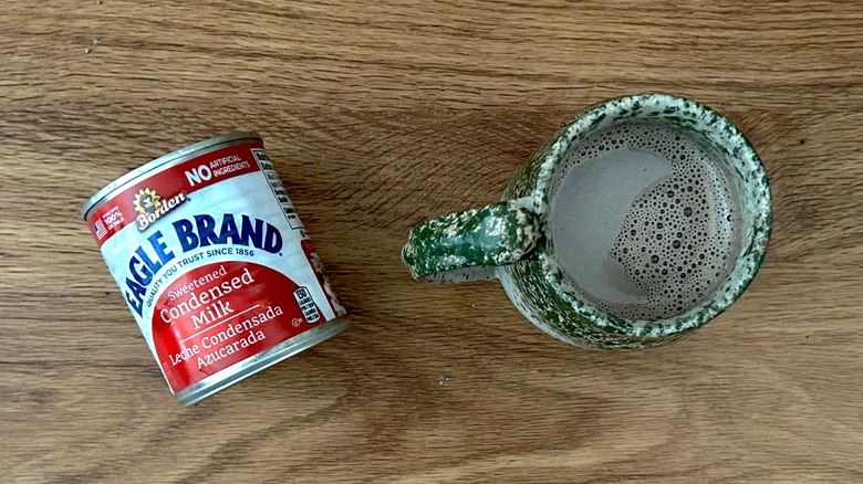Can of Eagle Brand Sweetened Condensed Milk and hot chocolate in a green mug