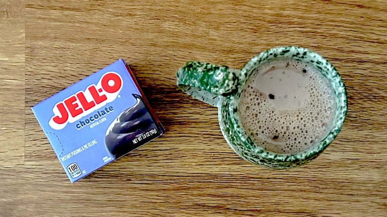 Box of chocolate instant pudding mix and hot chocolate in a green mug