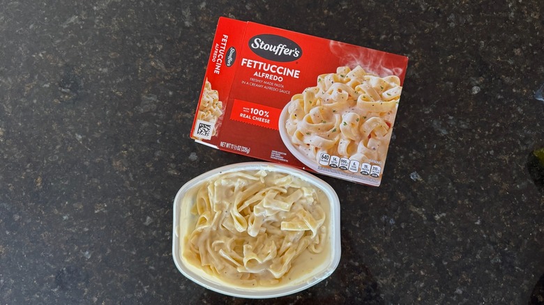 Package and tray of Stouffer's Fettuccine Alfredo on black countertop