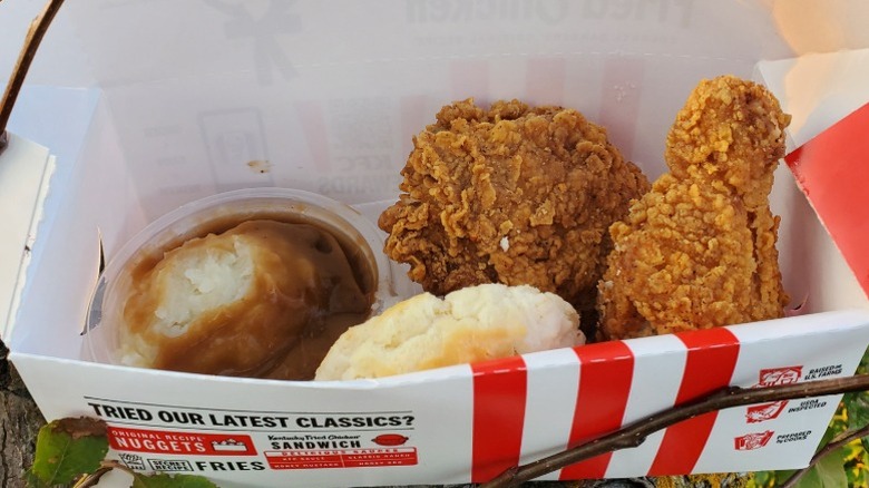 KFC fried chicken, biscuit, and mashed potatoes with gravy in a KFC box