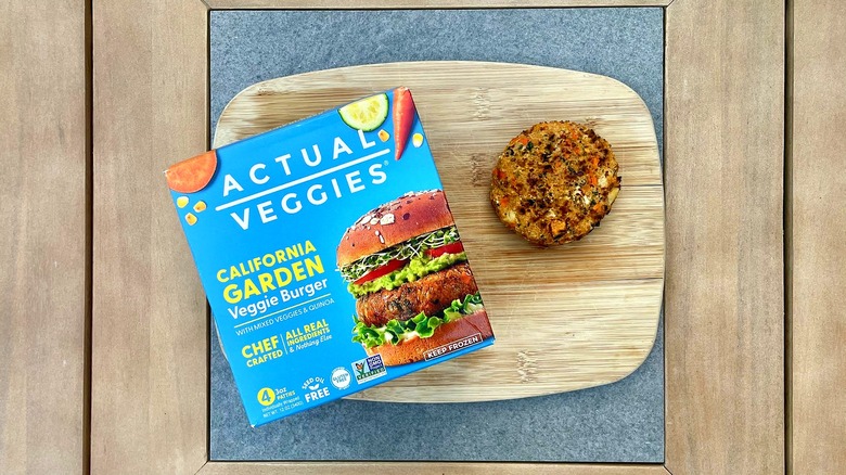 A box of Actual Veggies California Garden Burger on a cutting board next to a grilled patty